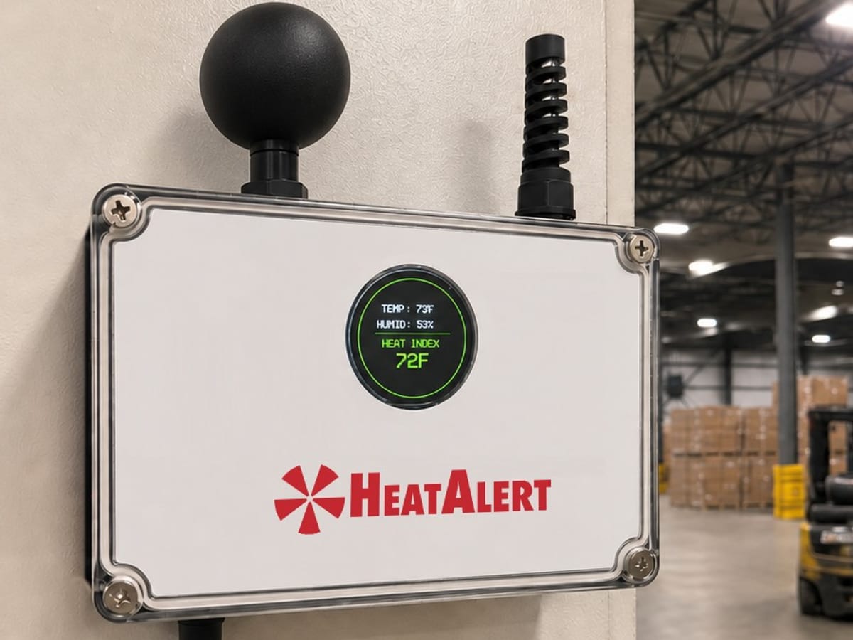 A HeatAlert WBGT unit on a warehouse wall: the globe probe on top, the live reading on its round display